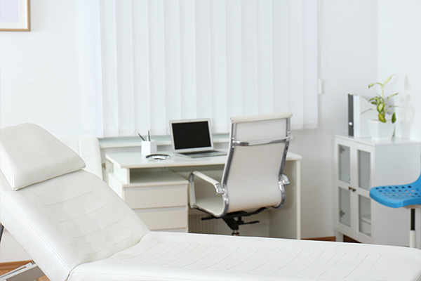 Dental chair in a modern office setting with a desk, computer monitor, and office equipment.