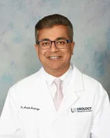 A man in a white lab coat posing for a portrait, smiling and looking directly at the camera.