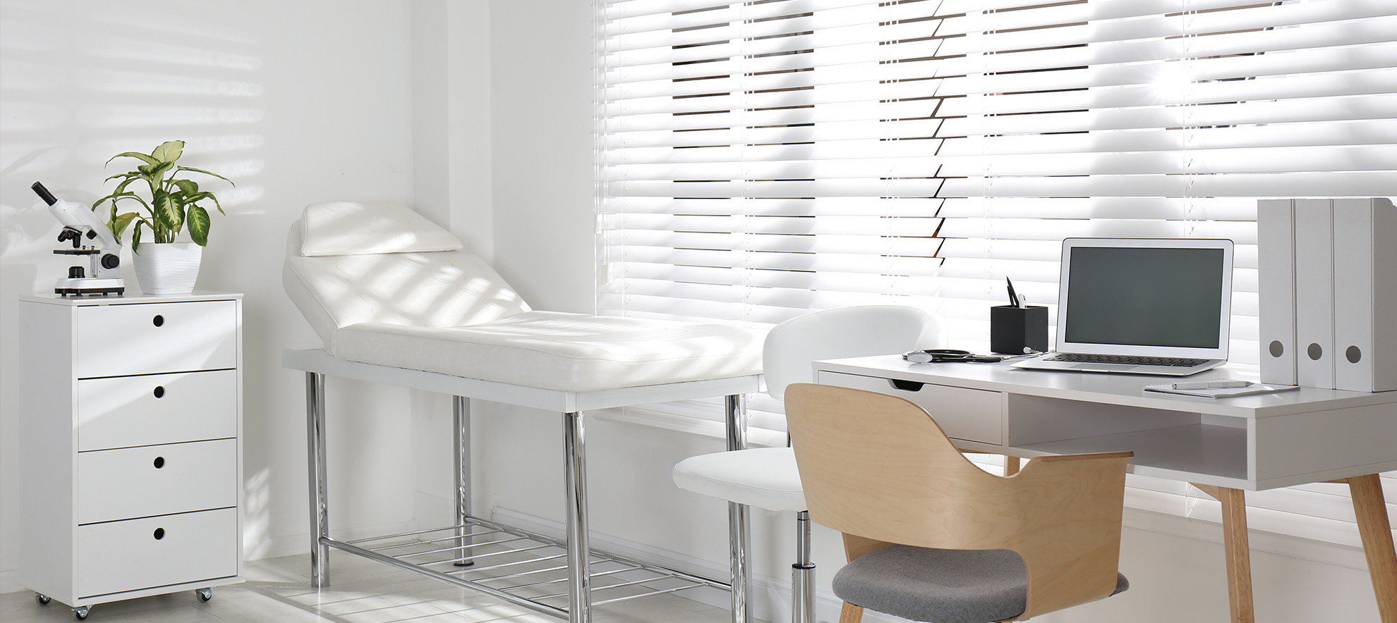 An image of a modern, well-lit home office with a desk, chair, computer monitor, and a window with white blinds.