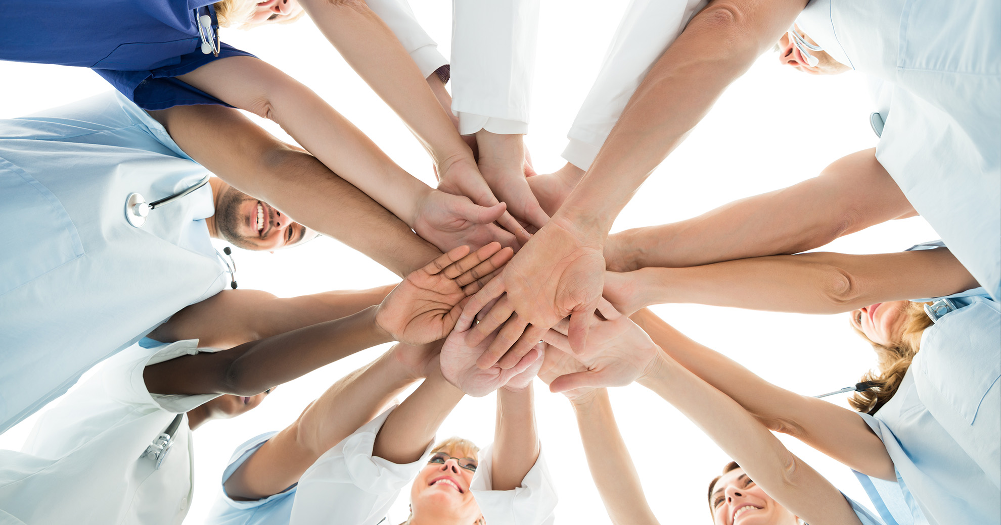 A diverse group of healthcare professionals, including doctors and nurses, joining hands in a circle, symbolizing unity and teamwork.