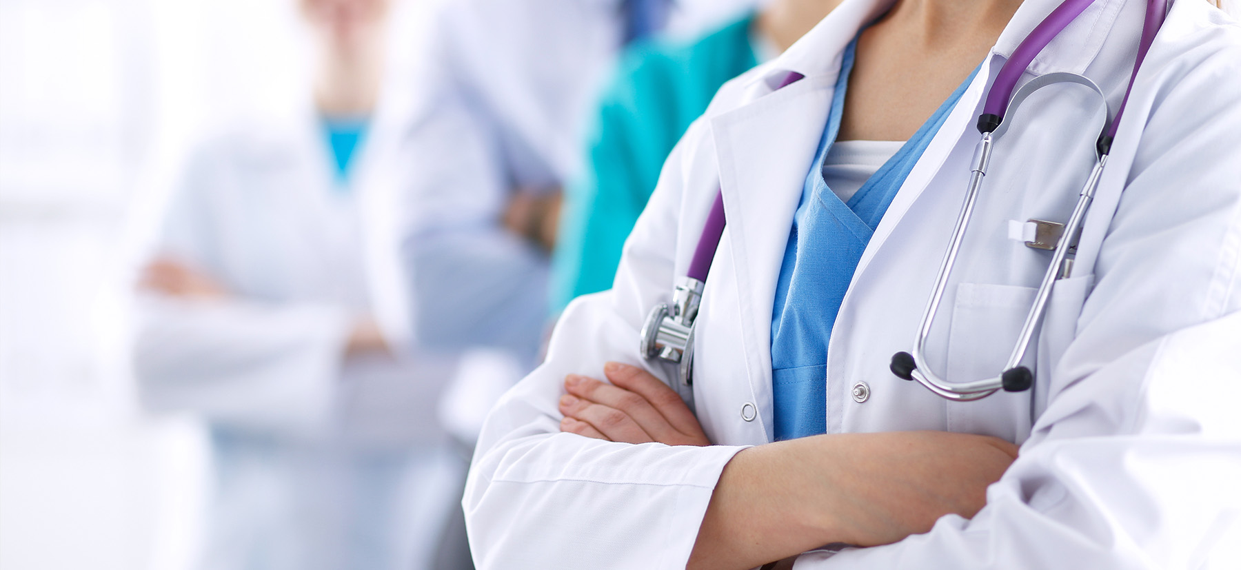 A group of healthcare professionals in white coats, standing with their arms crossed.