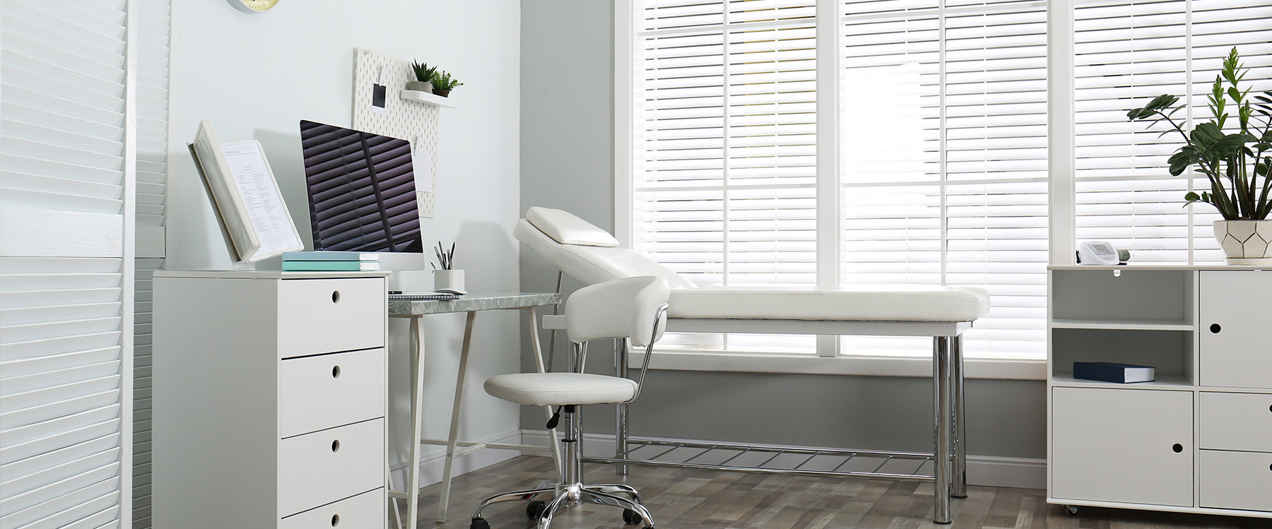 A modern dental office with a large window, white blinds, and professional furnishings.